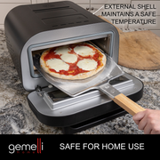 Gemelli Home Pizza Oven with a Neapolitan (Brick Oven Style) Pizza being removed on a pizza peel. Caption: Safe for Home Use, External Shell Maintains a Safe Temperature